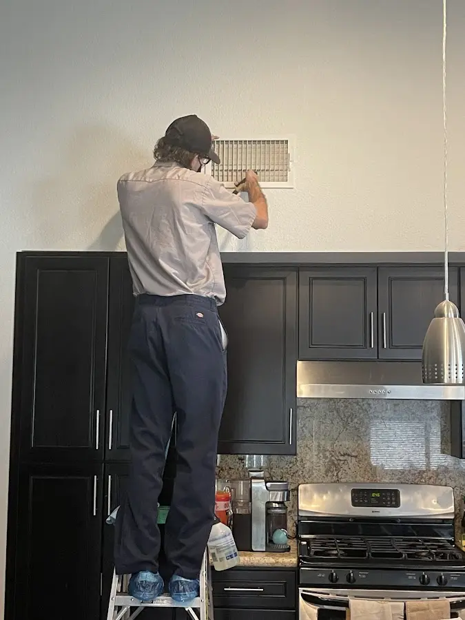 Technician inspecting an air vent during HVAC service in Lynnfield